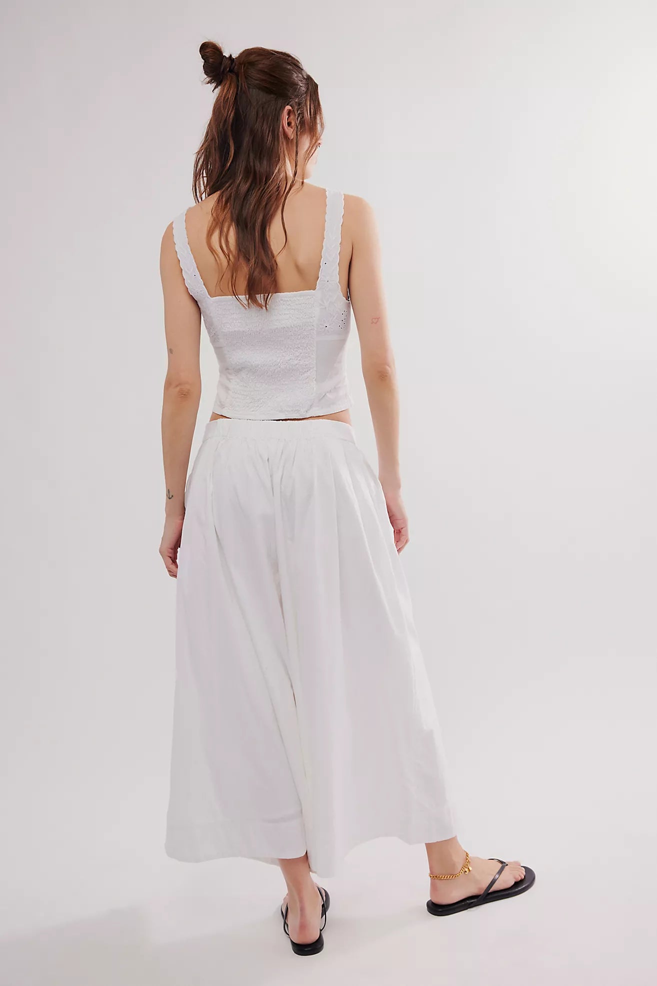Free People Into You Eyelet Set featuring a delicate eyelet fabric with a feminine design. The set includes a sleeveless top with a scoop neckline and matching high-waisted pants, offering a chic, lightweight look perfect for warm weather or casual outings, White