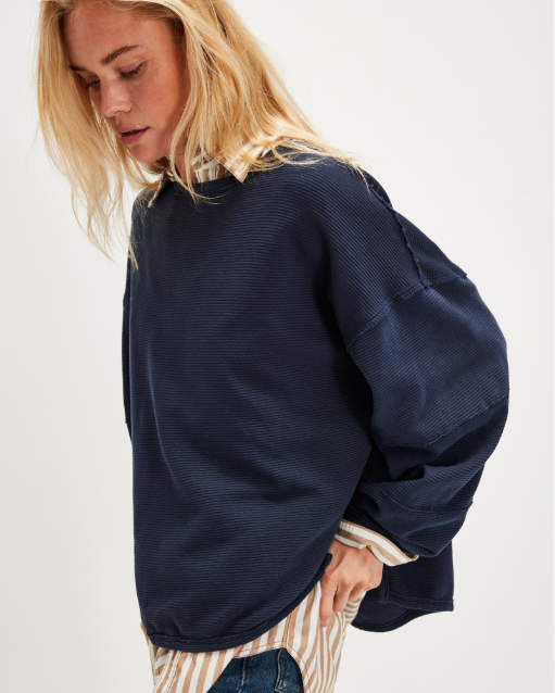 "We The Free Total Eclipse Tee" in an oversized, long-sleeve ribbed cotton fabric. The shirt features a wide scoop neckline, dropped shoulders, and exposed raw seams, Deeper Iris