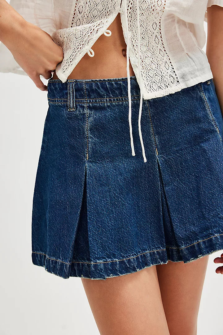 Free People Madison Ave Denim Mini Skirt with mid-rise waist, pleated design, rigid denim fabric, side zip closure, and belt loops, Wandering Eyes