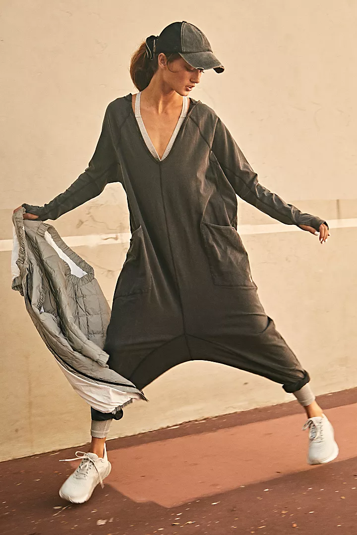 Free People Hot Shot Long Sleeve Onesie made from soft, stretchy fabric with a loose, relaxed design. This one-piece features a scoop neckline and long sleeves, offering a comfortable, laid-back fit that's perfect for layering or wearing on its own, Black