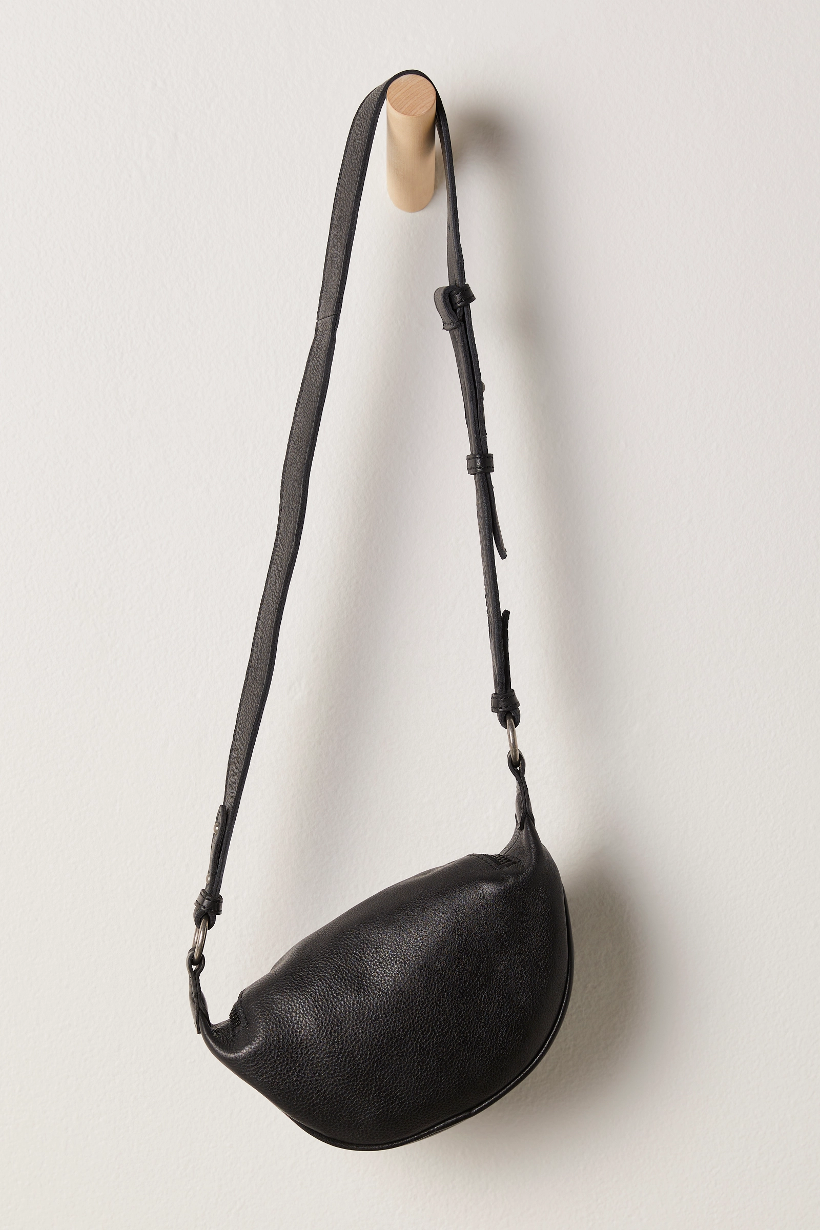 Free People Palmer Crossbody bag made from soft leather with a smooth, polished finish. This compact bag features an adjustable strap and a zippered main compartment, offering a stylish and functional accessory for everyday use, Black
