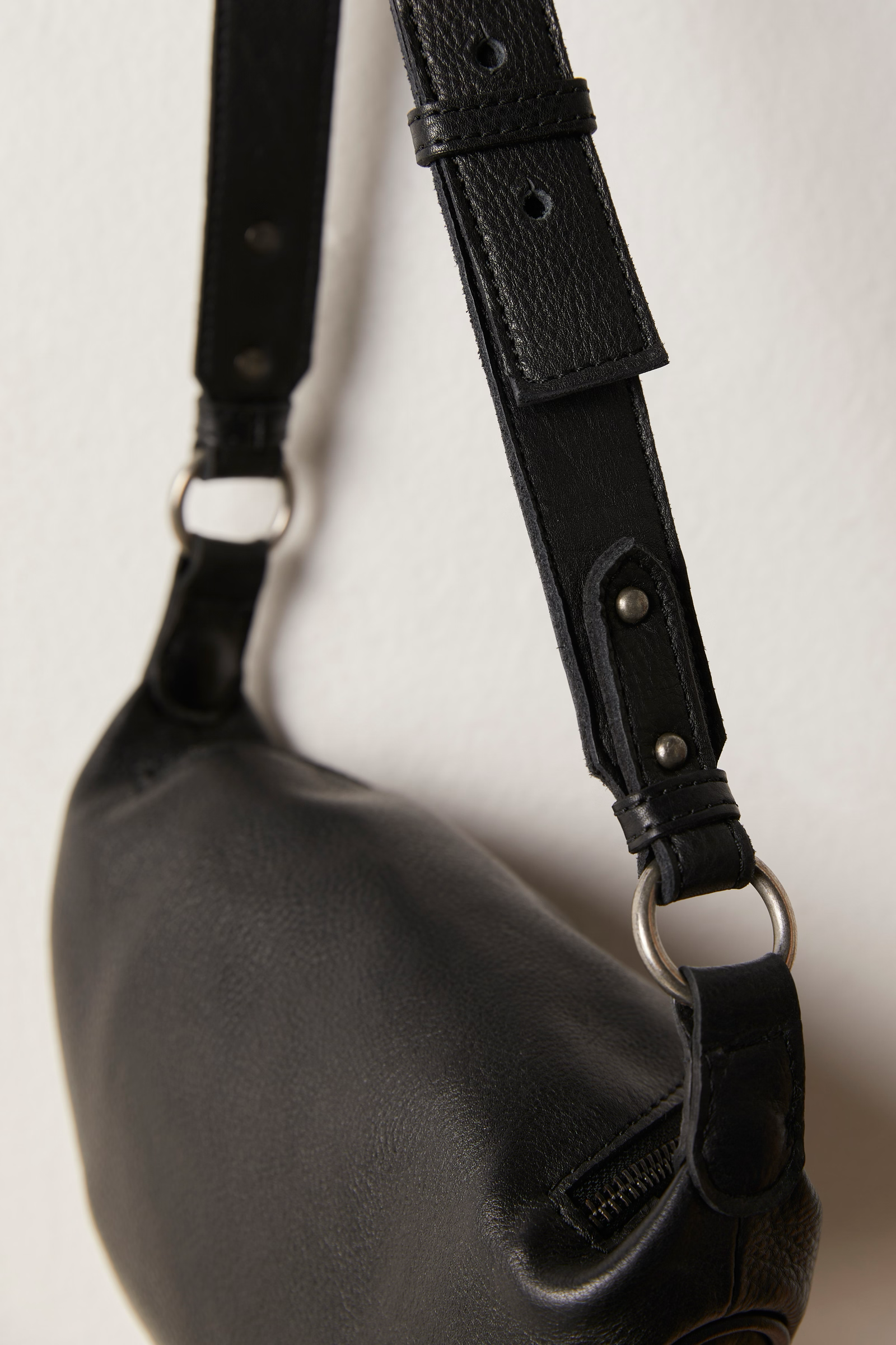 Free People Palmer Crossbody bag made from soft leather with a smooth, polished finish. This compact bag features an adjustable strap and a zippered main compartment, offering a stylish and functional accessory for everyday use, Black