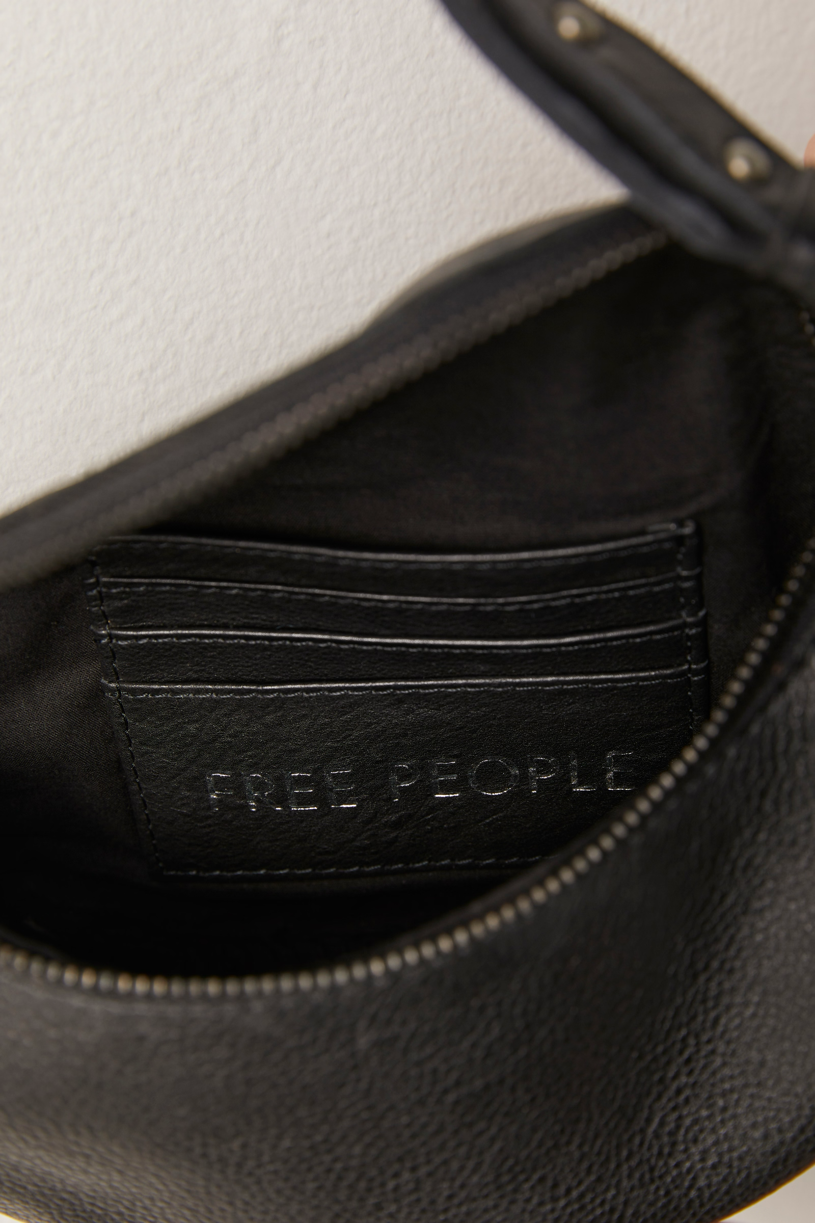 Free People Palmer Crossbody bag made from soft leather with a smooth, polished finish. This compact bag features an adjustable strap and a zippered main compartment, offering a stylish and functional accessory for everyday use, Black