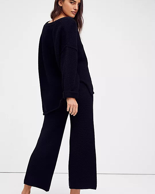 Free People Hailee Sweater Set featuring a soft, ribbed knit long-sleeve sweater and matching high-waisted, wide-leg pants. The relaxed fit of both pieces offers a comfortable and stylish look, perfect for lounging or casual outings, Black