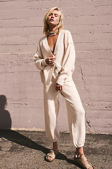 Free People Hailee Cardi Set featuring a soft, knit fabric with a relaxed fit. The set includes a long-sleeve, open-front cardigan and matching knit pants, offering a cozy and stylish look, perfect for casual wear or lounging, Powder Sand