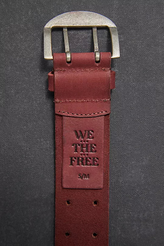 We The Free Double Cross Belt made from distressed leather with a bold, double-cross buckle design. This adjustable belt adds a rustic, boho-inspired touch to any outfit, perfect for pairing with jeans or dresses, Oxblood