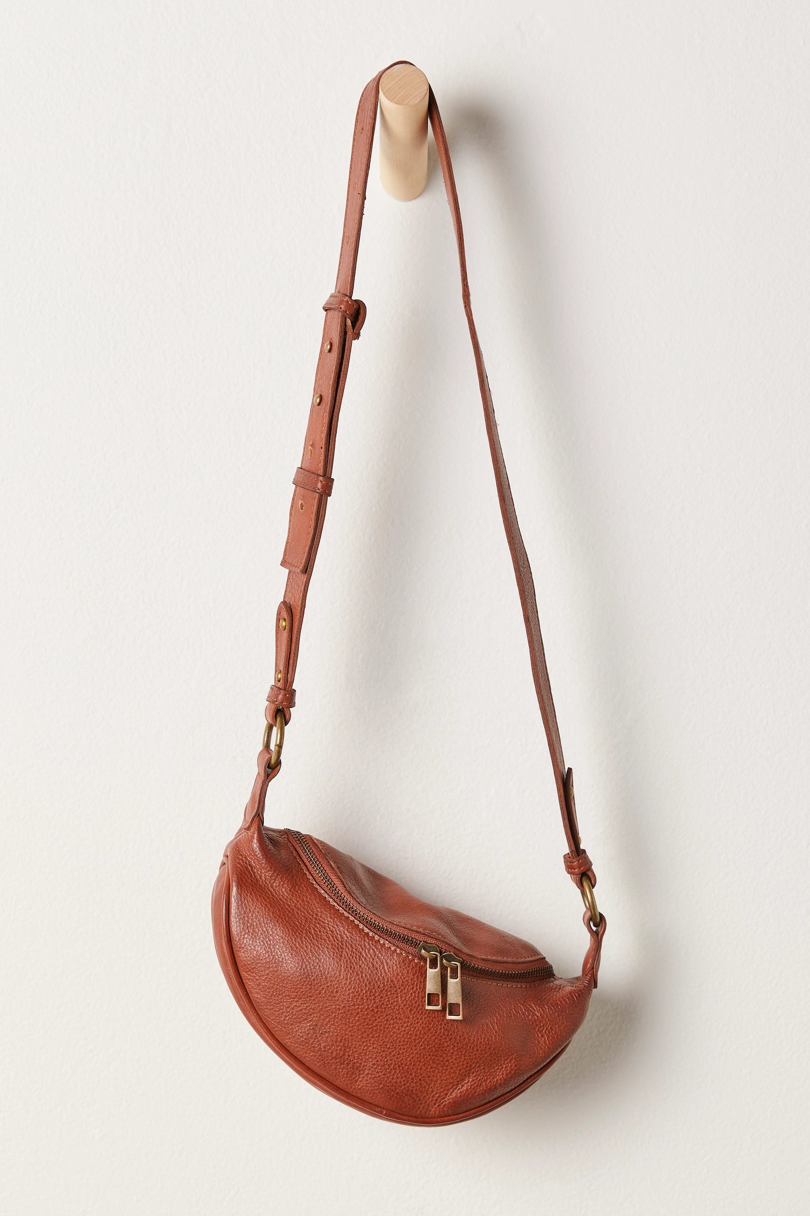 Free People Palmer Crossbody bag made from soft leather with a smooth, polished finish. This compact bag features an adjustable strap and a zippered main compartment, offering a stylish and functional accessory for everyday use, Spiced Rum