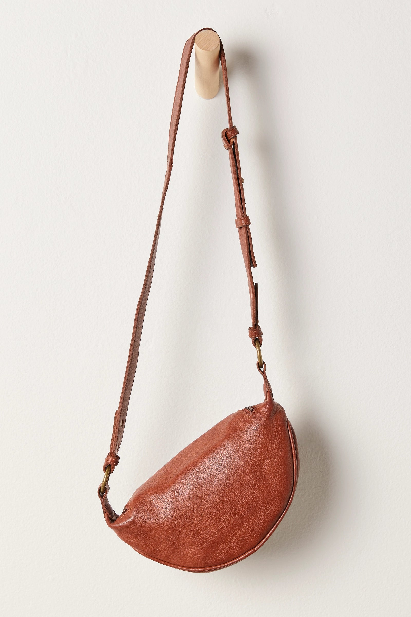 Free People Palmer Crossbody bag made from soft leather with a smooth, polished finish. This compact bag features an adjustable strap and a zippered main compartment, offering a stylish and functional accessory for everyday use, Spiced Rum