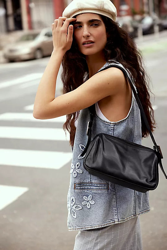 Free People Arm Candy Bag in luxe leather with a thick adjustable strap, rivet detailing, and a zip-top closure, Black